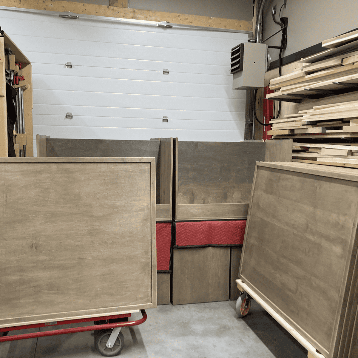 Custom wood furniture pieces in a workshop, showcasing unfinished cabinetry and tabletops, emphasizing craftsmanship and quality materials for Beaver Custom Builds.