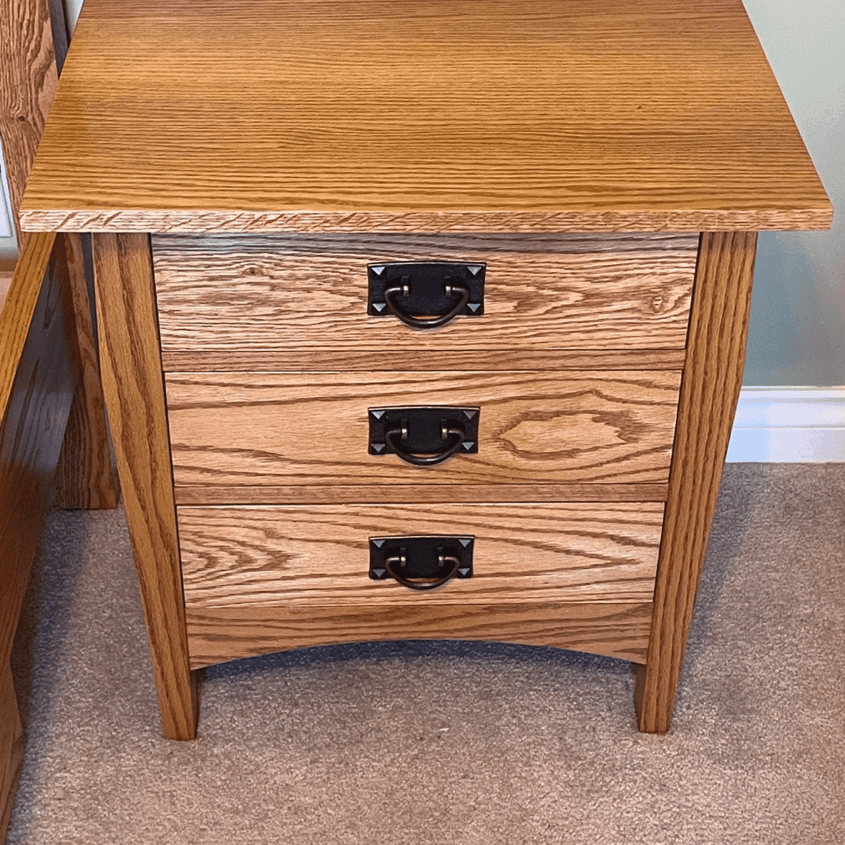 Custom wooden nightstand with three drawers, featuring black metal handles, showcasing quality craftsmanship by Beaver Custom Builds.