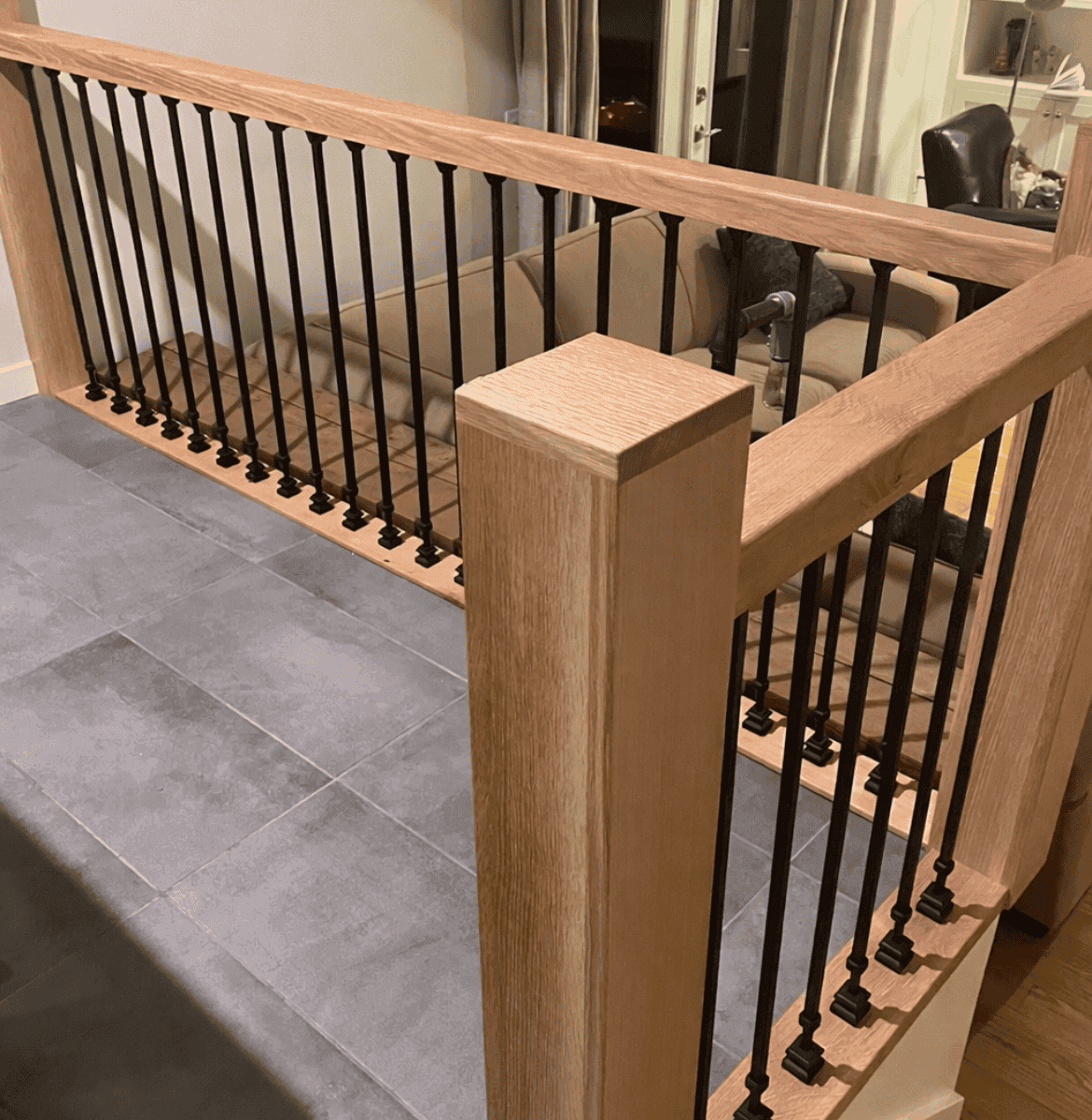 Custom wooden railing with black metal balusters, showcasing craftsmanship in a modern interior setting, highlighting Beaver Custom Builds' attention to detail in woodworking projects.