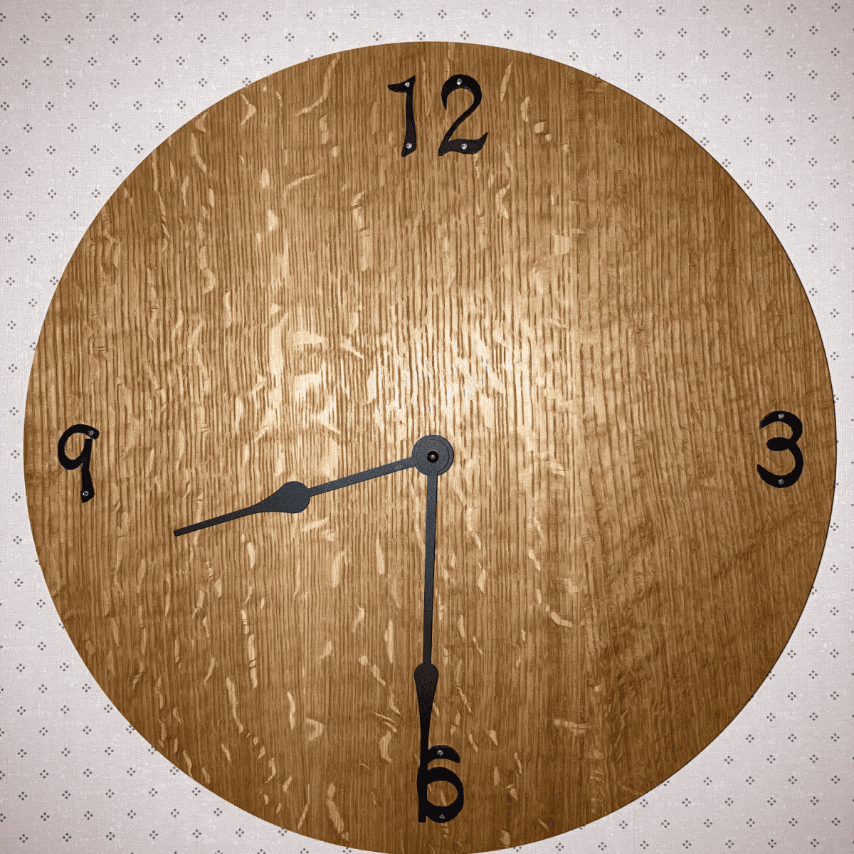 Wooden wall clock design featuring black hour markers and hands, showcasing craftsmanship in custom woodworking, suitable for home decor.
